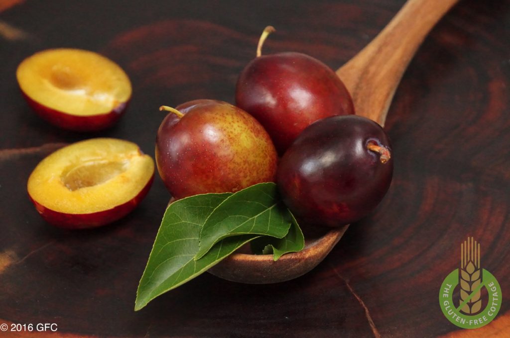 Fresh plums and plum halves (gluten-free plum cake).